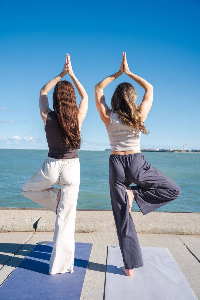 KSP03546 two women, in yoga tree pose, in front of body of water